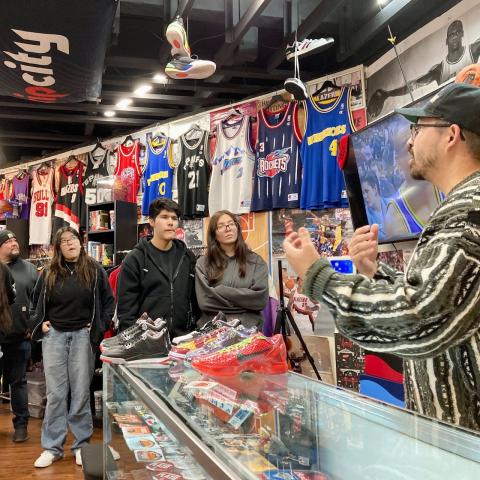 students in a shirt shop listening to business owner