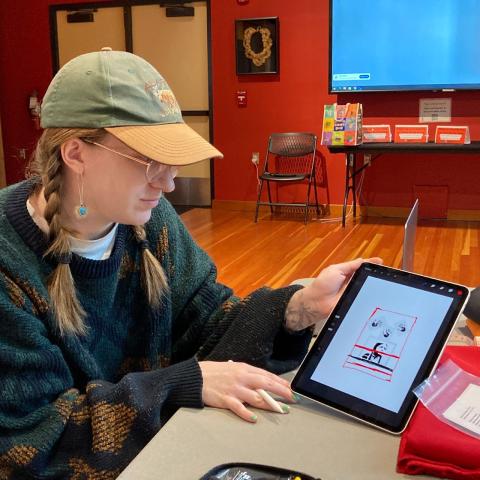 student sitting with tablet showing off designs